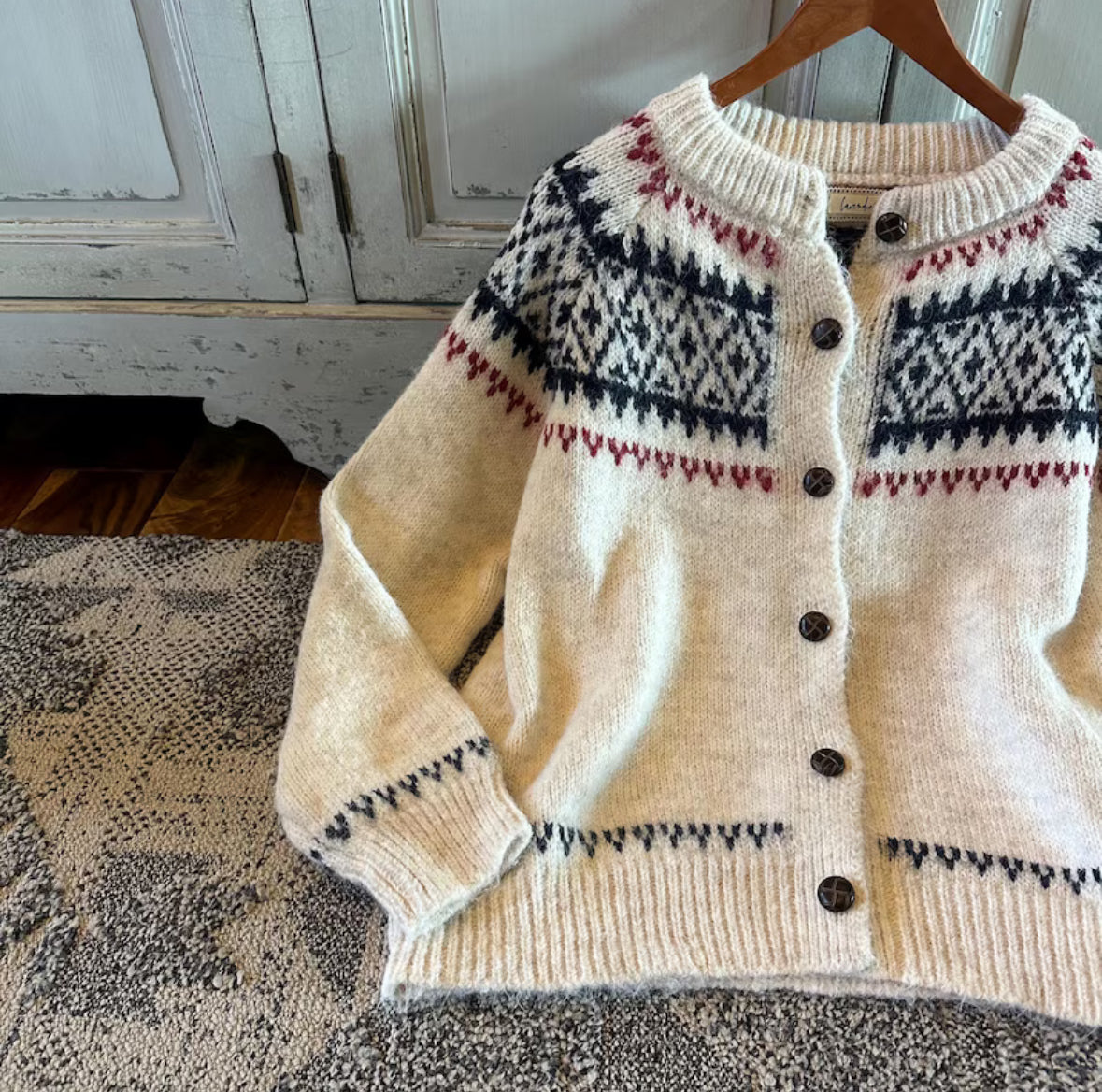 Knitted cardigan with a pattern on a wooden hanger against a rustic background
