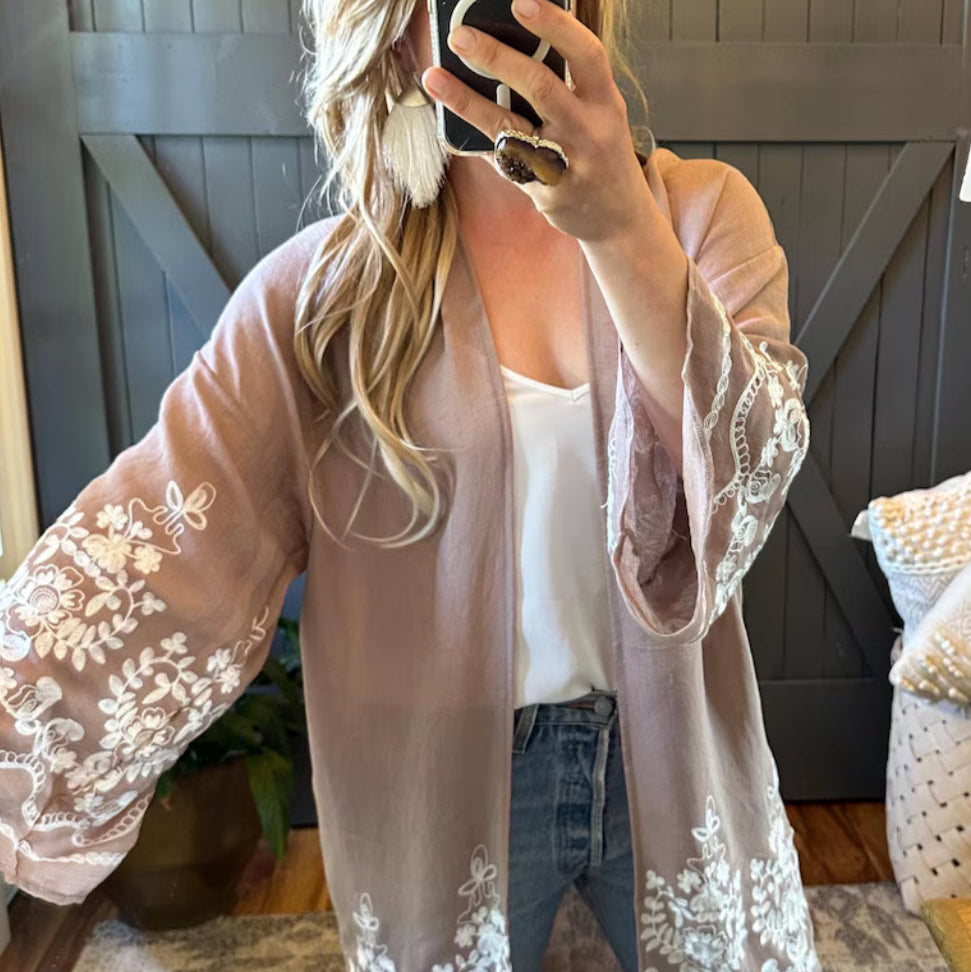 Woman wearing a light pink lace-trimmed cardigan in a home setting.