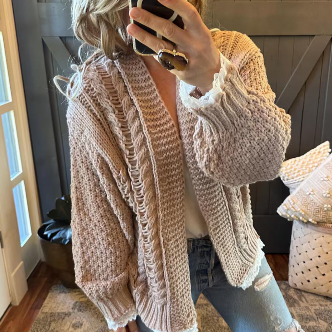 Person wearing a beige knitted cardigan in a home setting