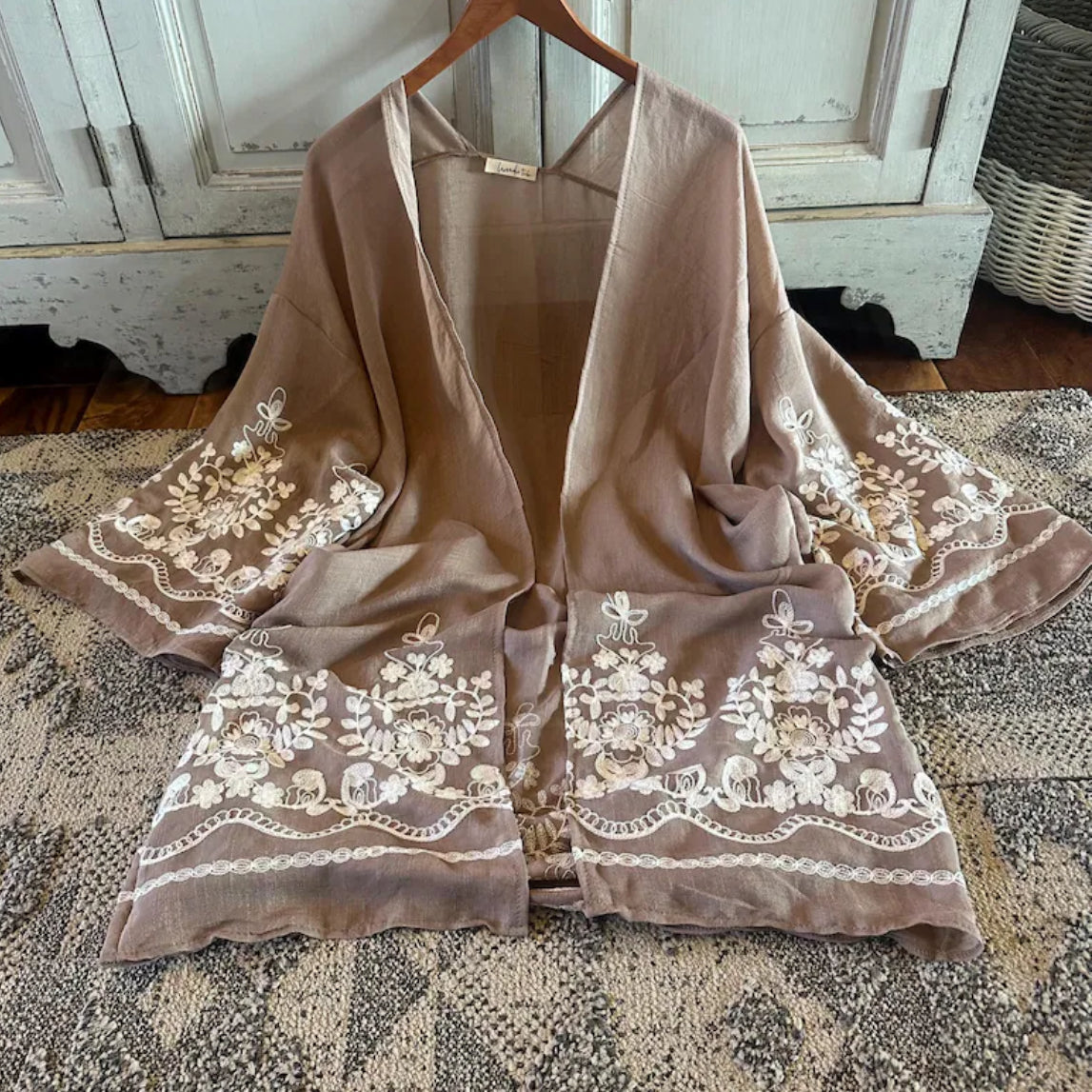 Brown embroidered garment on a hanger with a rustic background