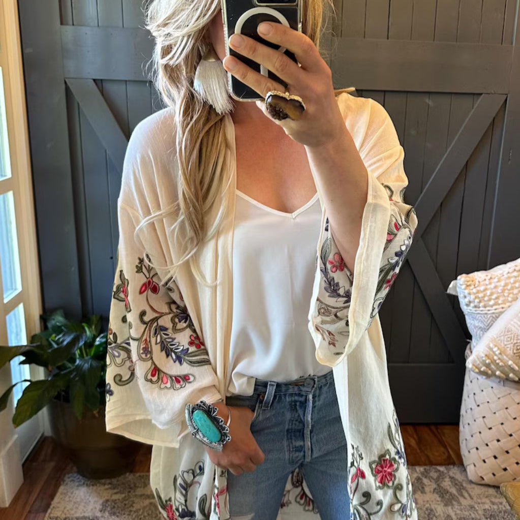 Person wearing a floral embroidered cardigan in a home setting