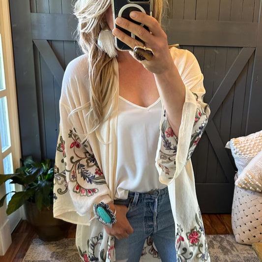 Person wearing a floral embroidered cardigan in a home setting