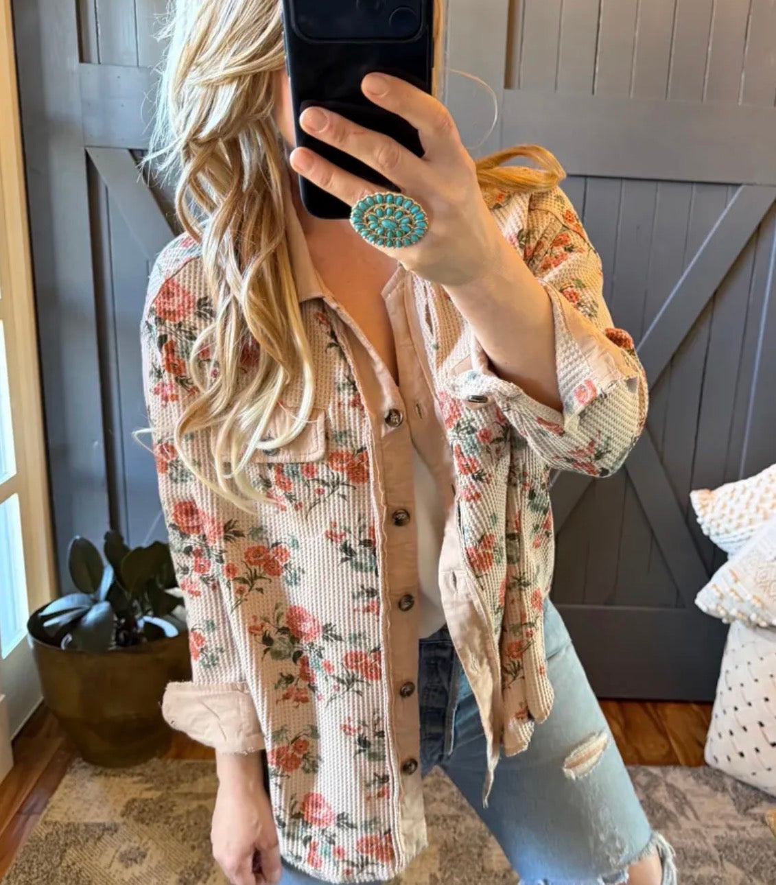 Person wearing a floral cardigan taking a mirror selfie.