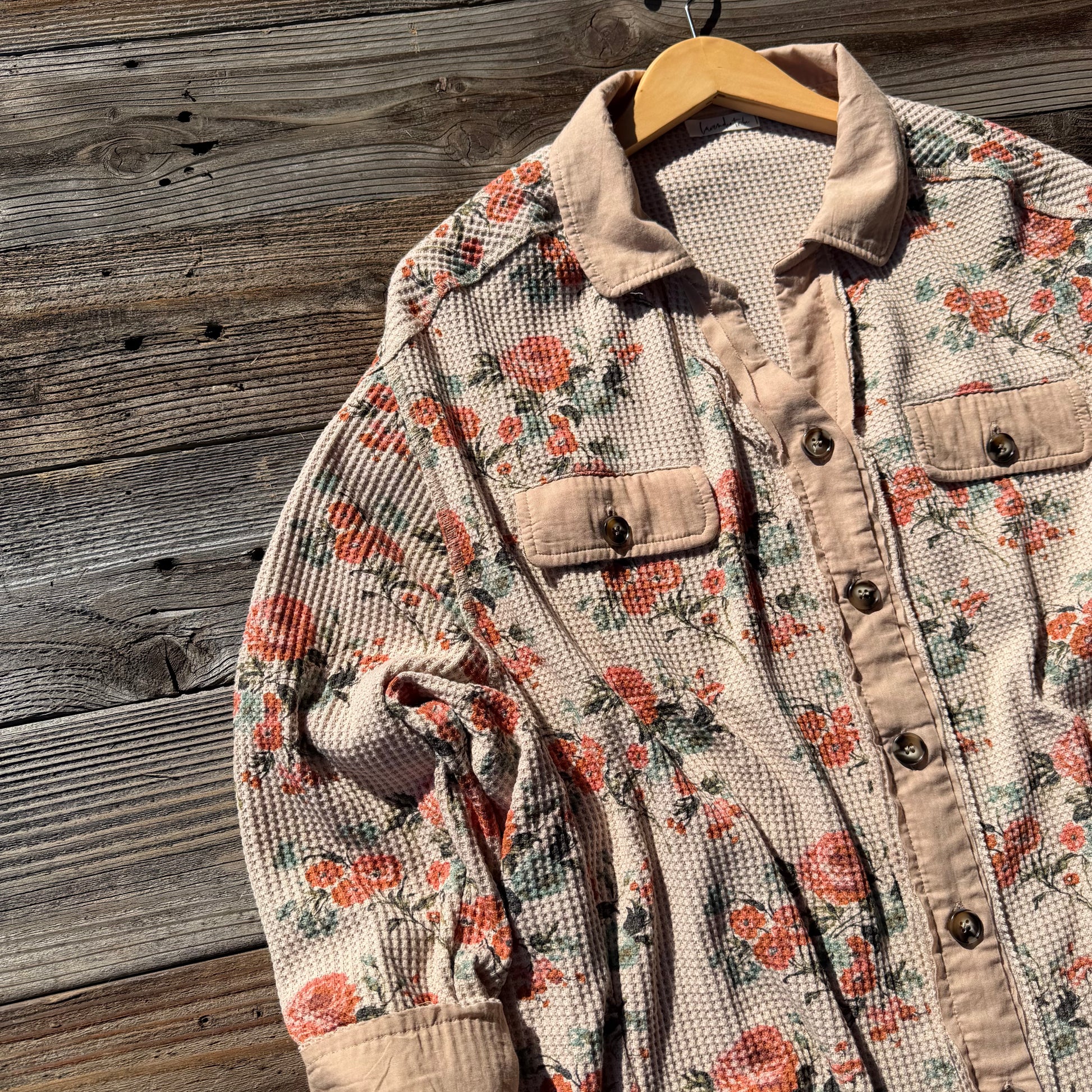 Floral patterned jacket on a wooden hanger against a wooden background