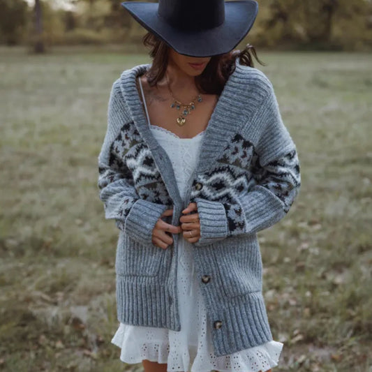 Woman wearing a patterned gray cardigan and white dress in a field
