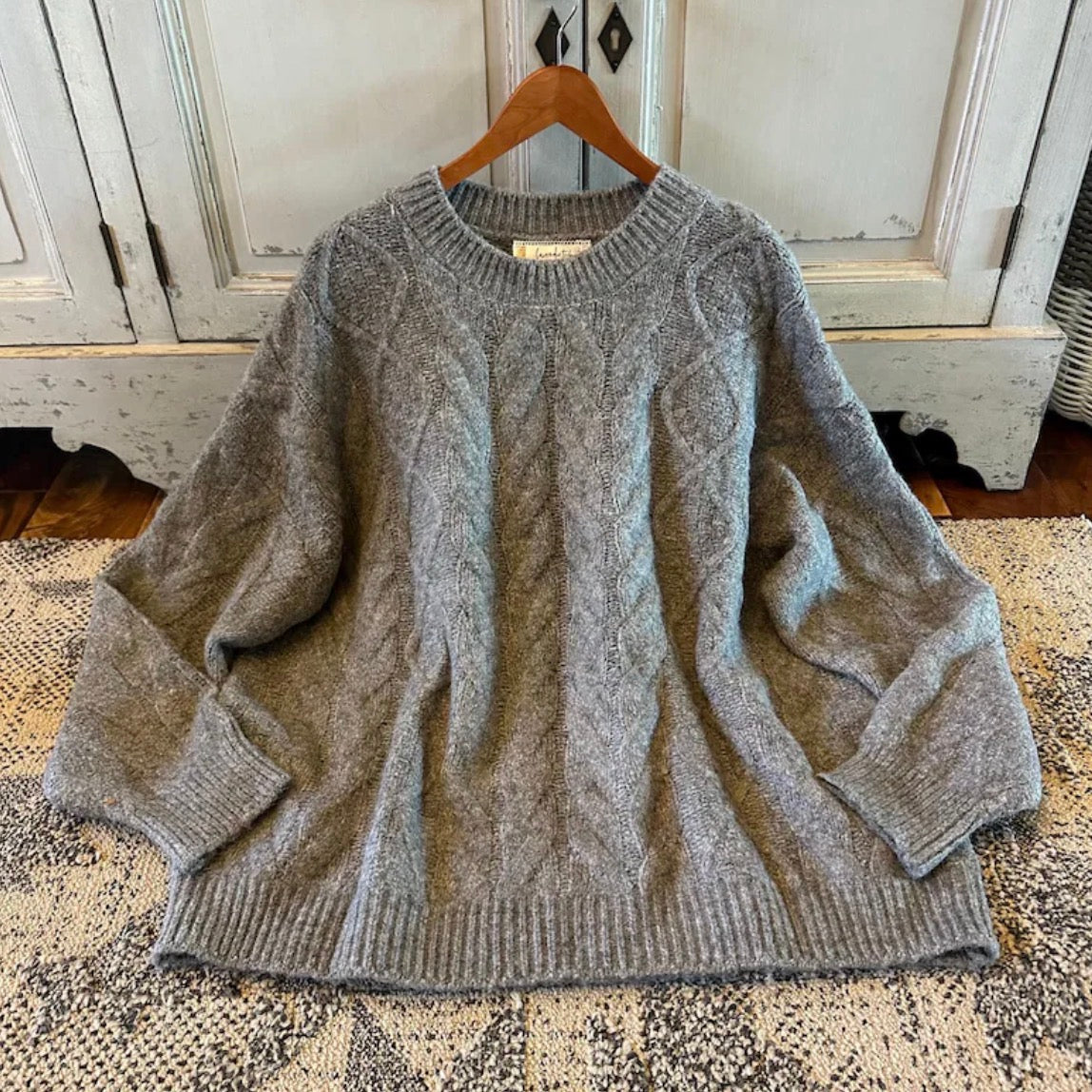 Gray sweater on a wooden hanger against a rustic wooden door background