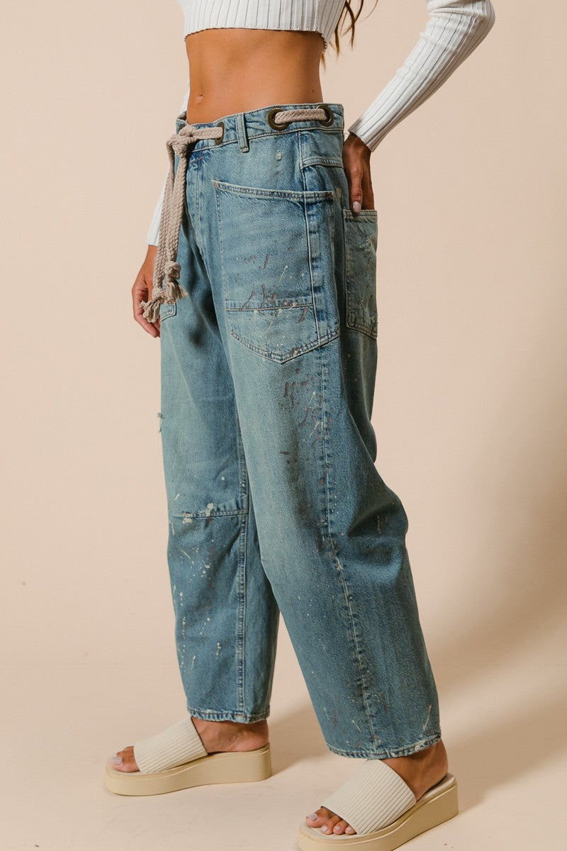 Person wearing blue jeans and white sandals on a beige background