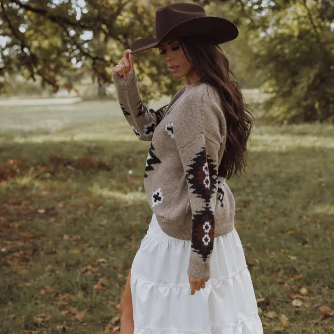 Woman wearing a patterned sweater and white skirt outdoors