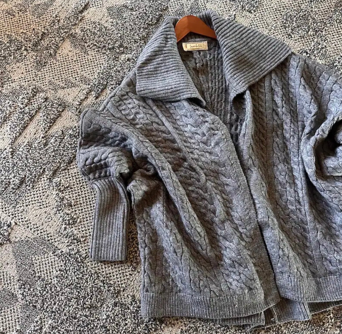 Gray cable knit cardigan on a textured surface