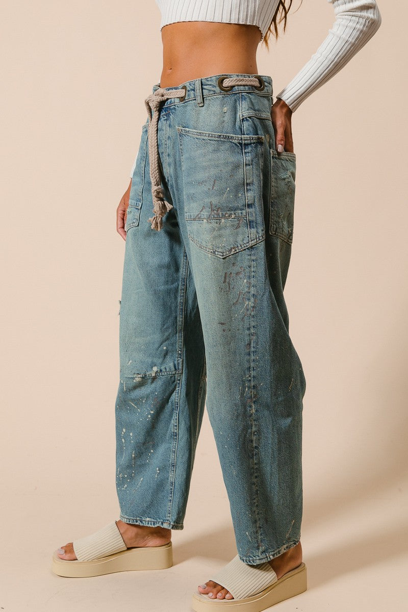 Person wearing blue jeans with a beige background