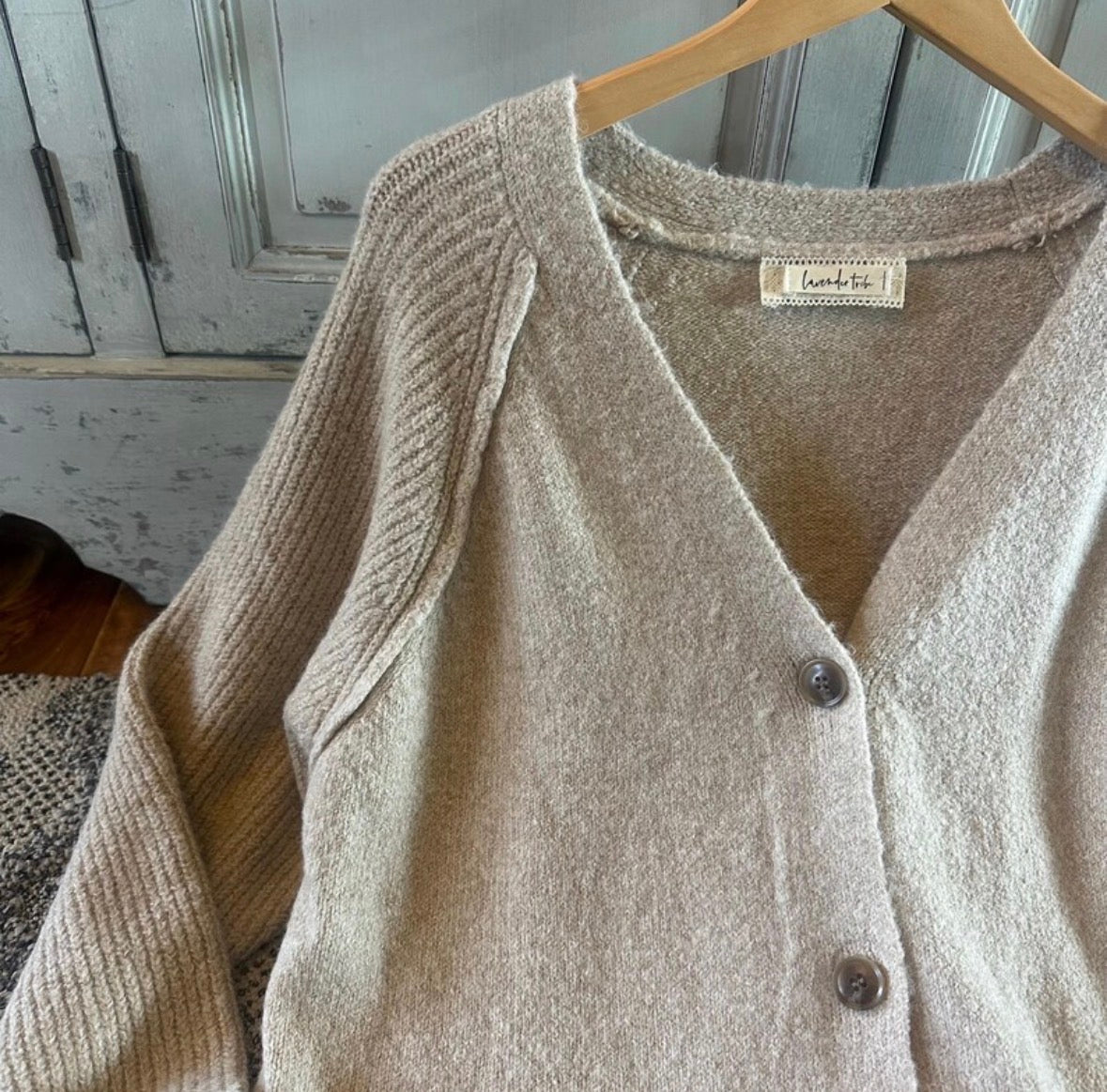 Beige cardigan on a hanger with a rustic background