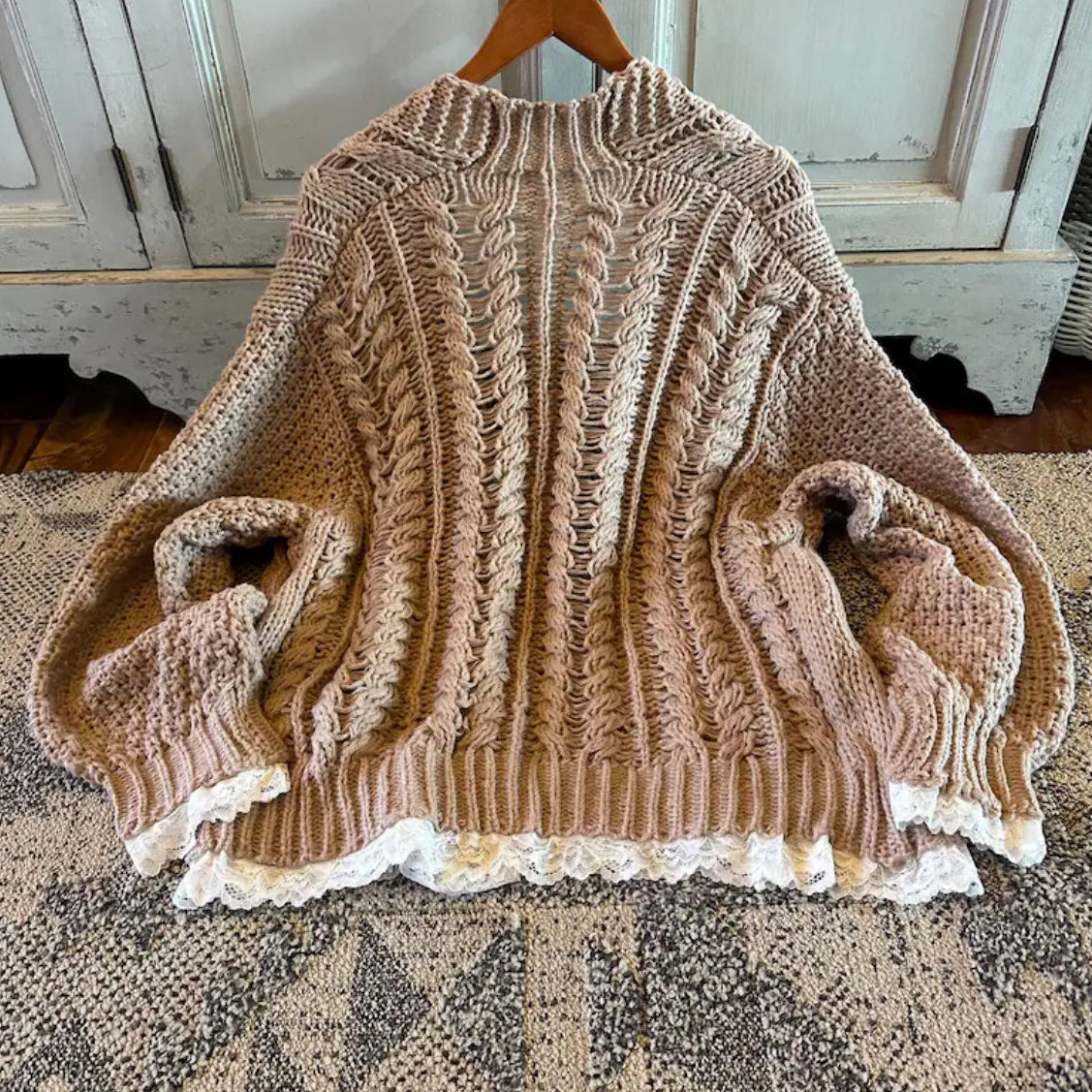 Knitted sweater with lace trim on a textured surface