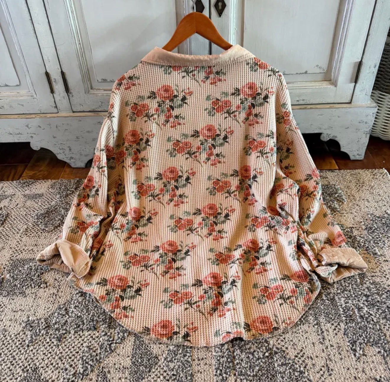Floral patterned shirt on a hanger against a rustic background