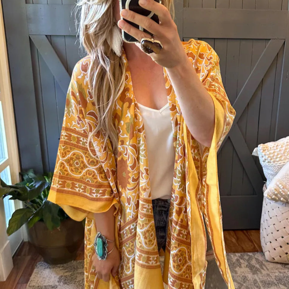 Person wearing a yellow patterned kimono in a room with wooden paneling.
