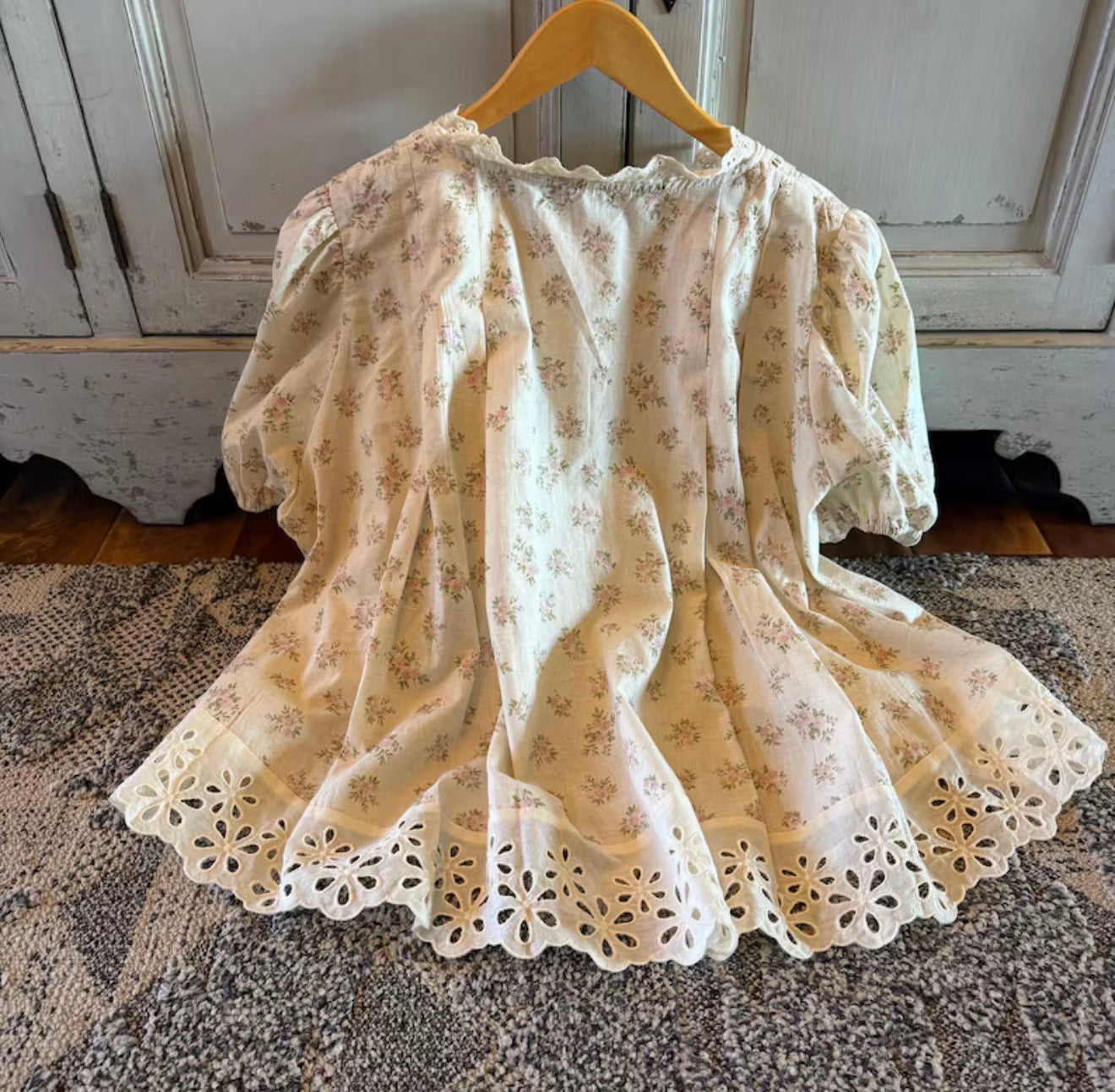Floral lace dress on a wooden hanger against a rustic background