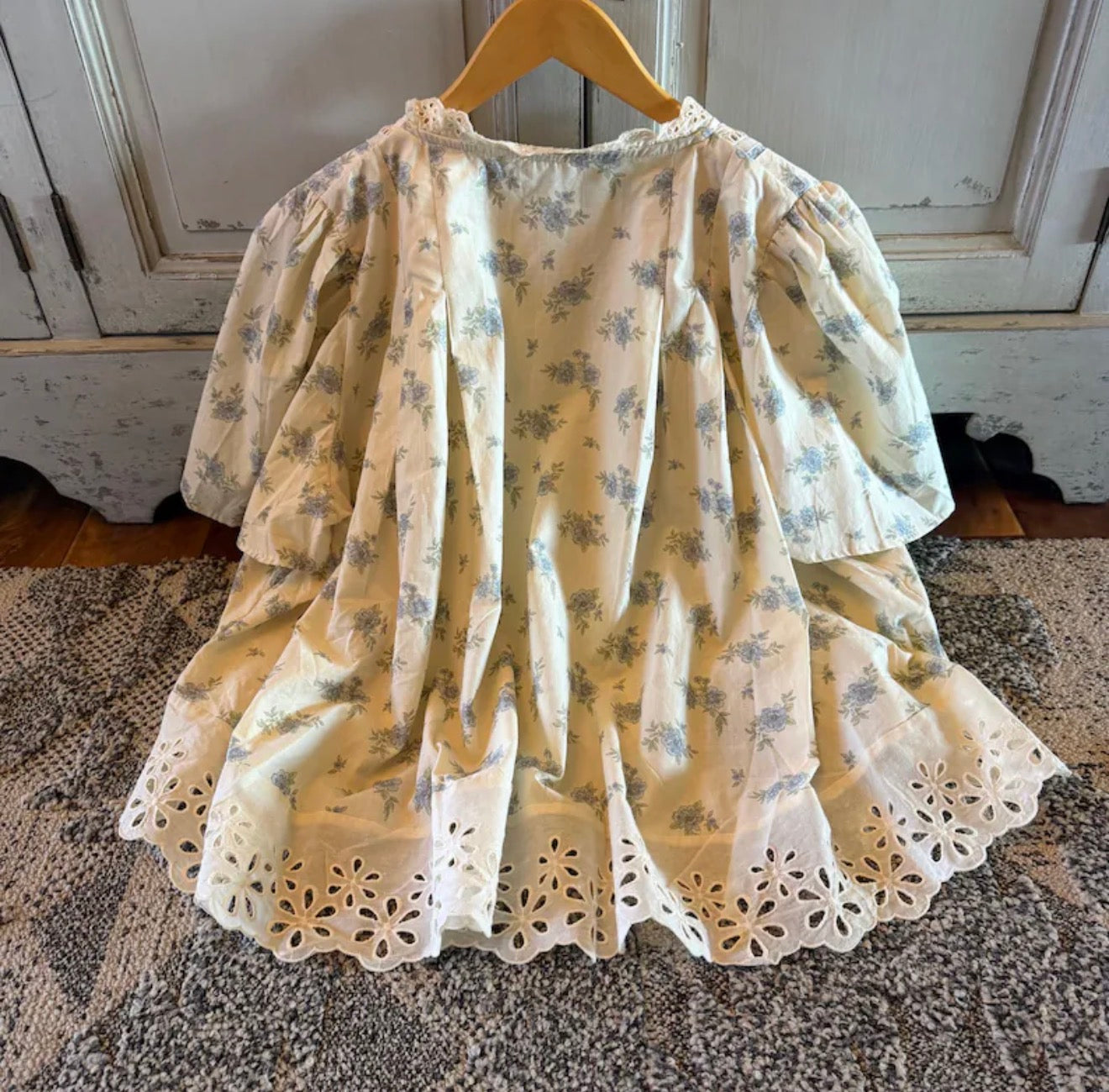 Floral dress with lace details on a wooden hanger against a rustic background