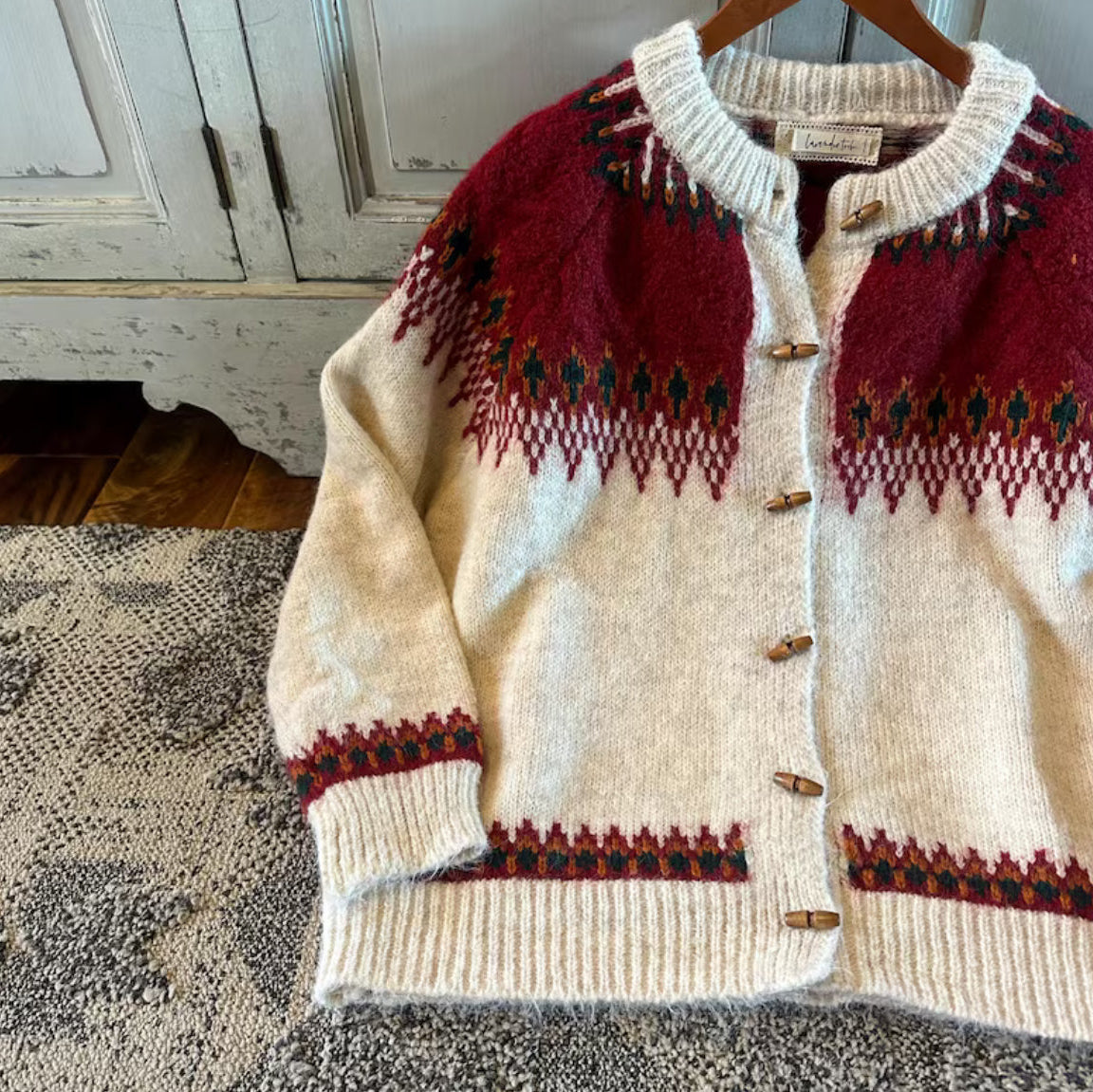 Knitted cardigan with red and green patterns on a textured surface