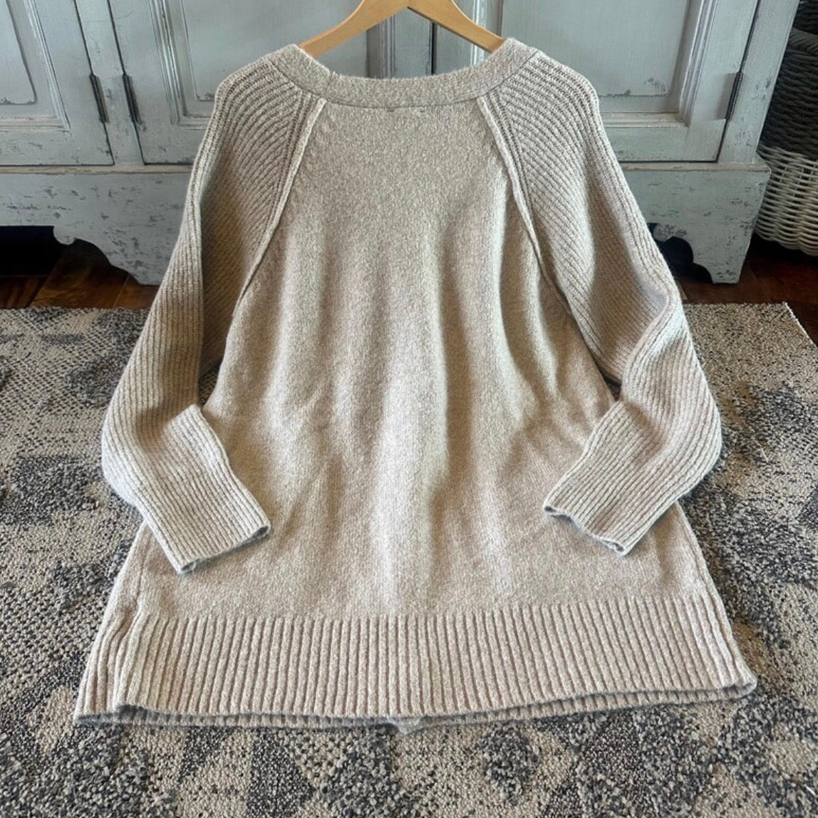 Beige sweater on a hanger against a neutral background