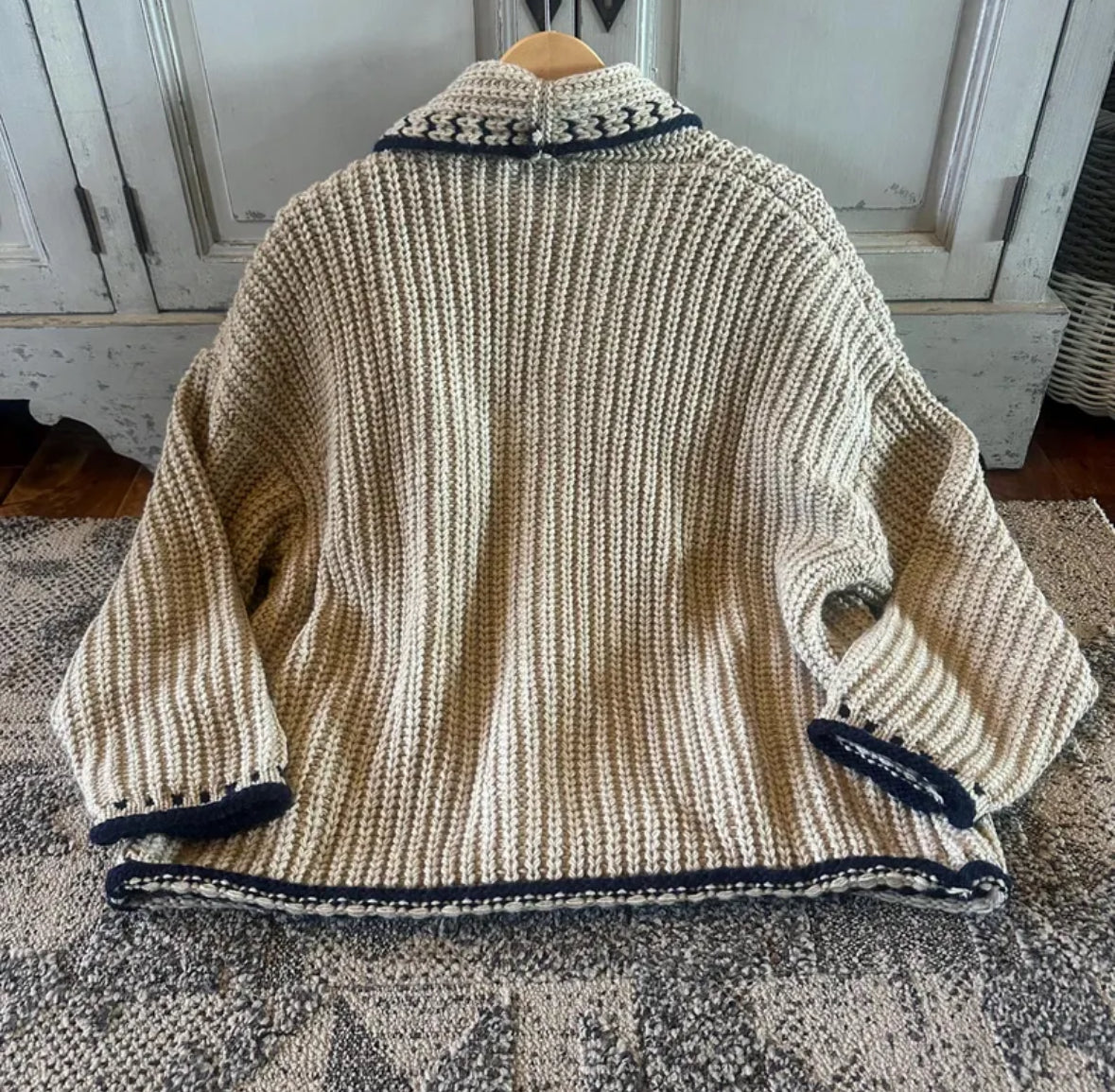 Knitted jacket with navy trim on a textured surface