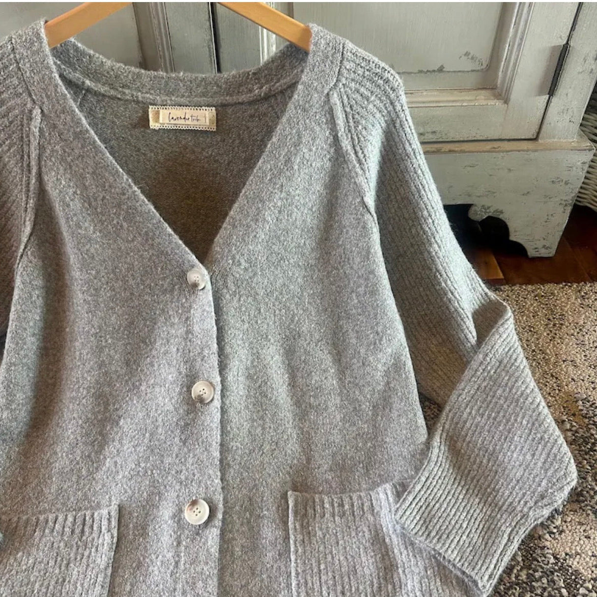 Gray cardigan on a hanger with a blurred indoor background