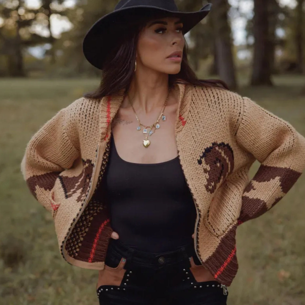 Woman wearing a patterned cardigan and black hat in an outdoor setting