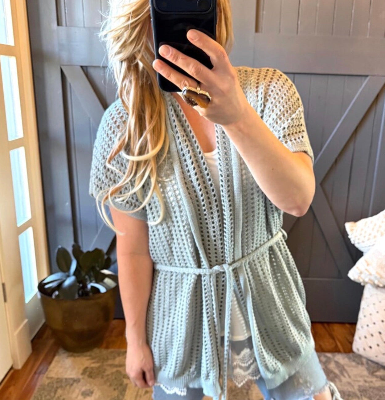 Person wearing a light blue crochet cover-up in a home setting.