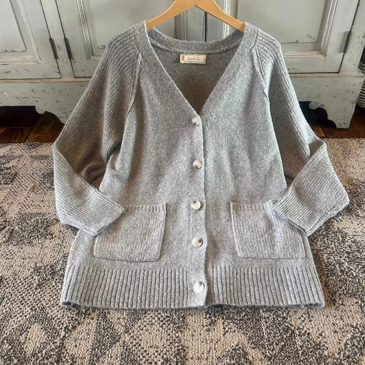 Gray cardigan on a hanger against a rustic wooden background