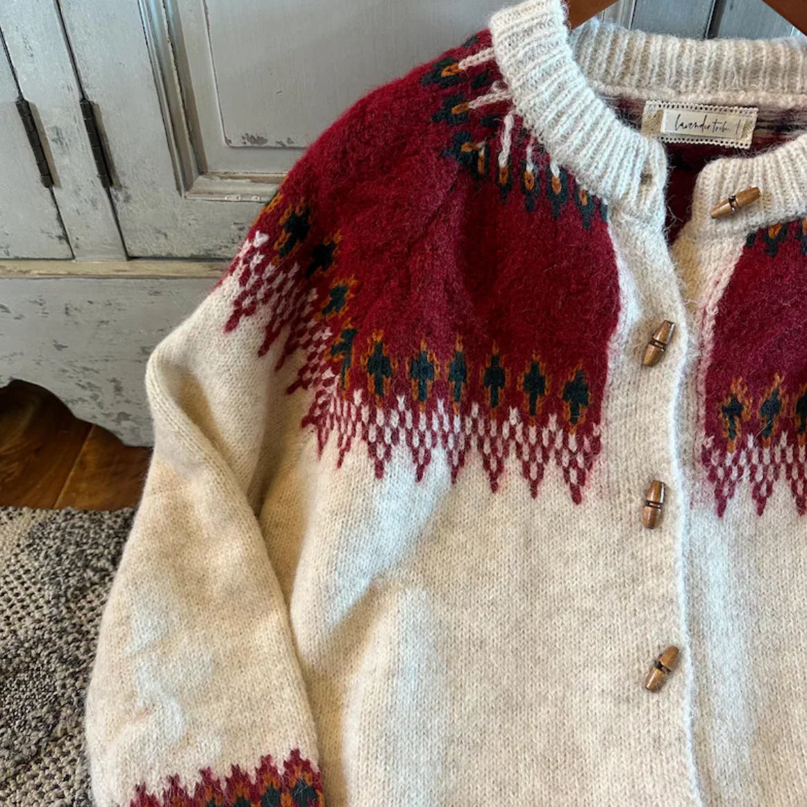 Two cardigans with a red and beige pattern on a wooden floor.