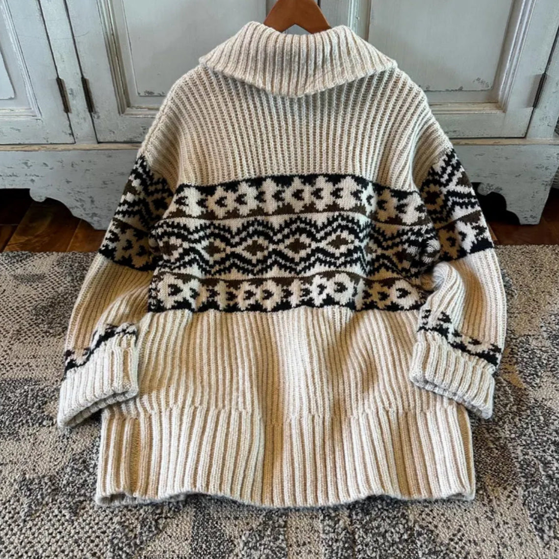 Knitted sweater with a patterned design draped over a wooden chair.