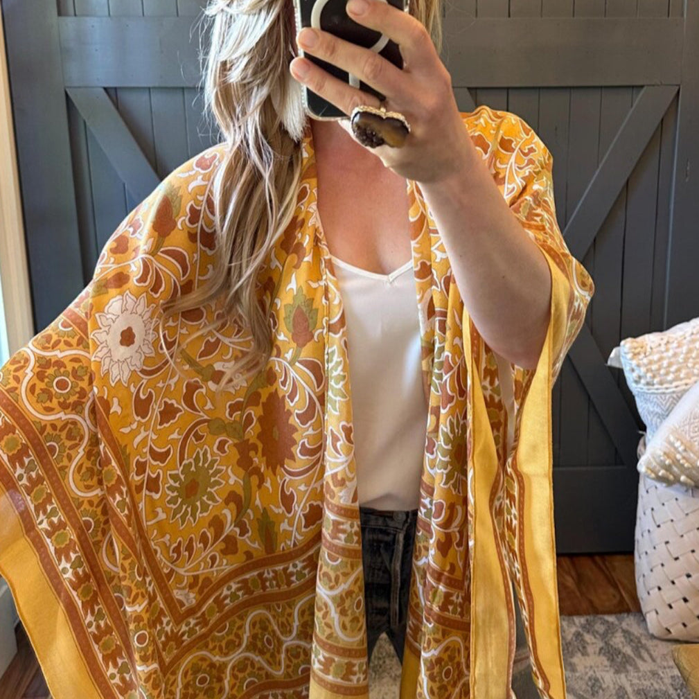 Person wearing a yellow patterned scarf in front of a wooden door.