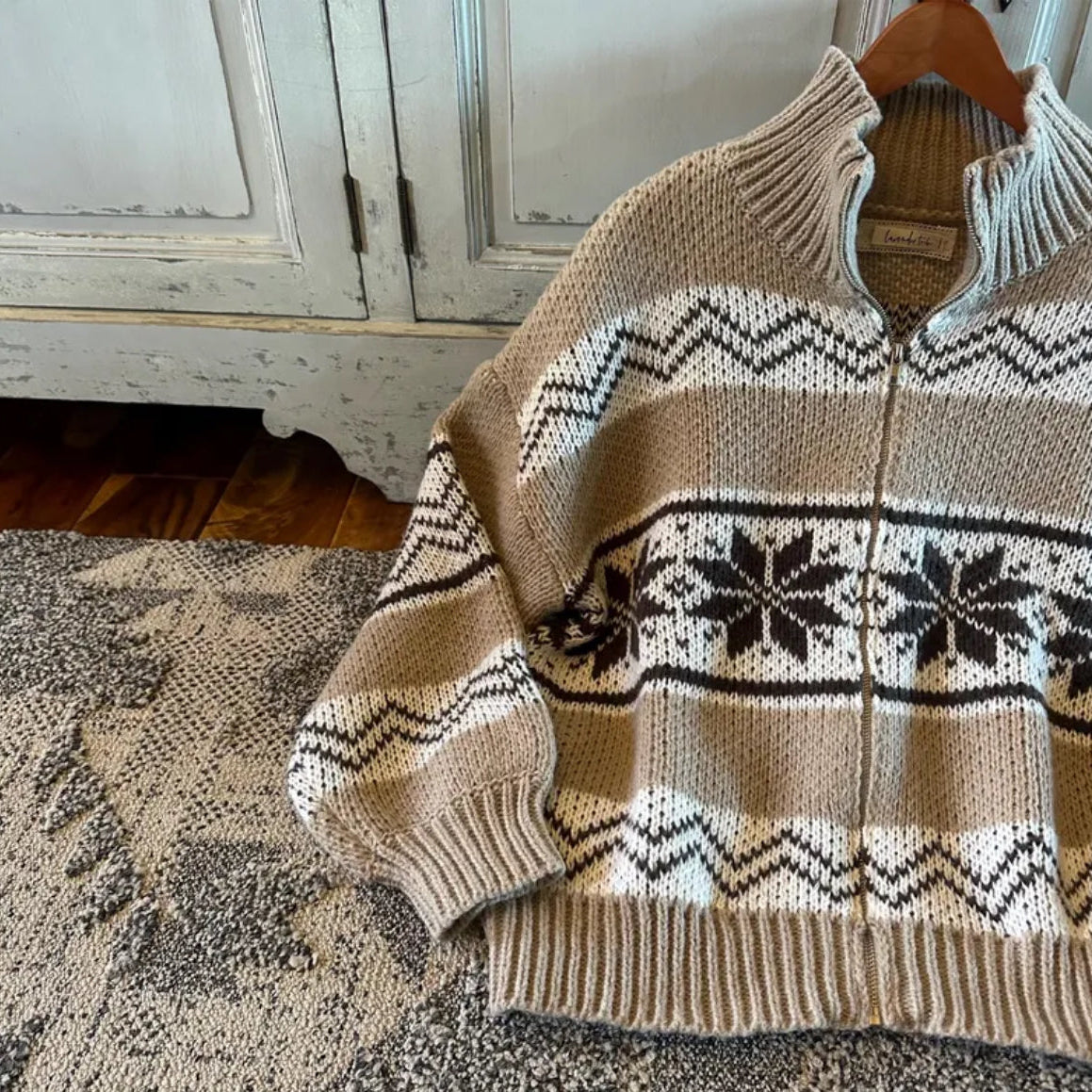Knitted sweater with a pattern on a hanger against a wooden cabinet background
