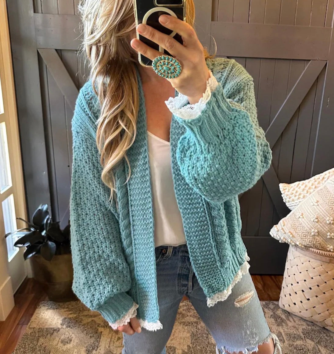 Person wearing a light blue knitted cardigan in a home setting.