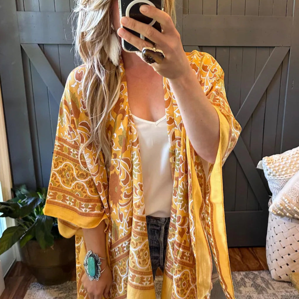 Person wearing a yellow patterned kimono taking a mirror selfie.