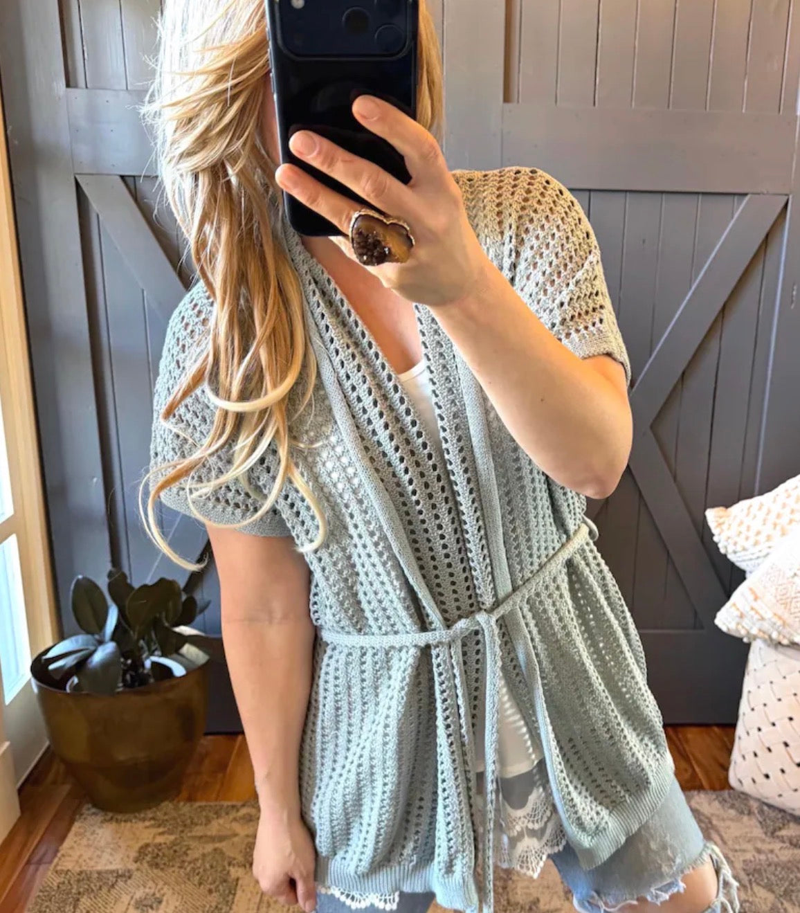 Person wearing a light blue crochet dress taking a mirror selfie.