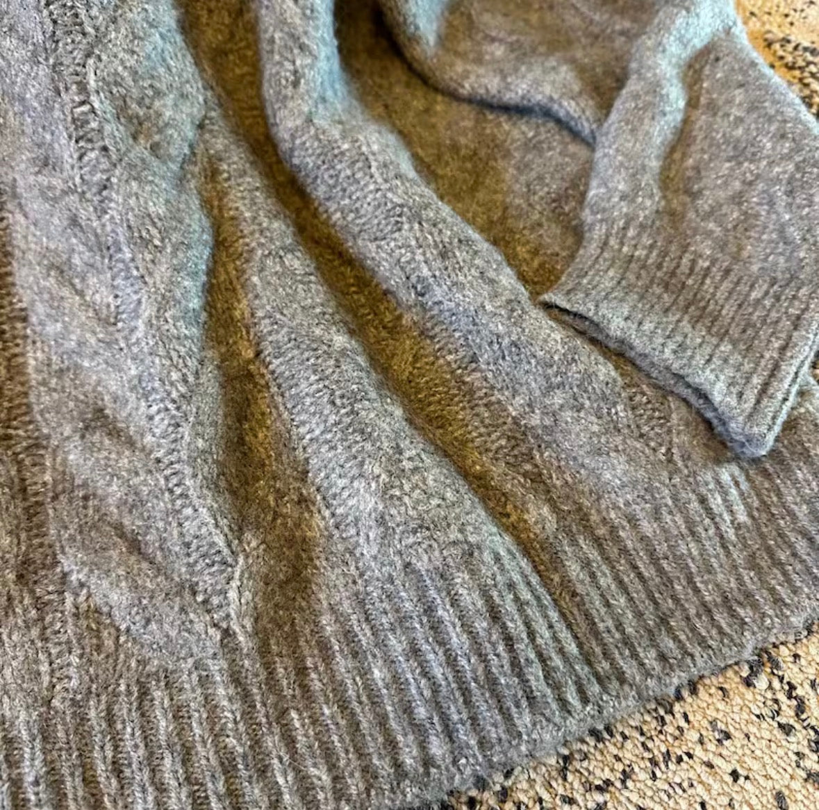 Close-up of a textured beige sweater on a neutral background
