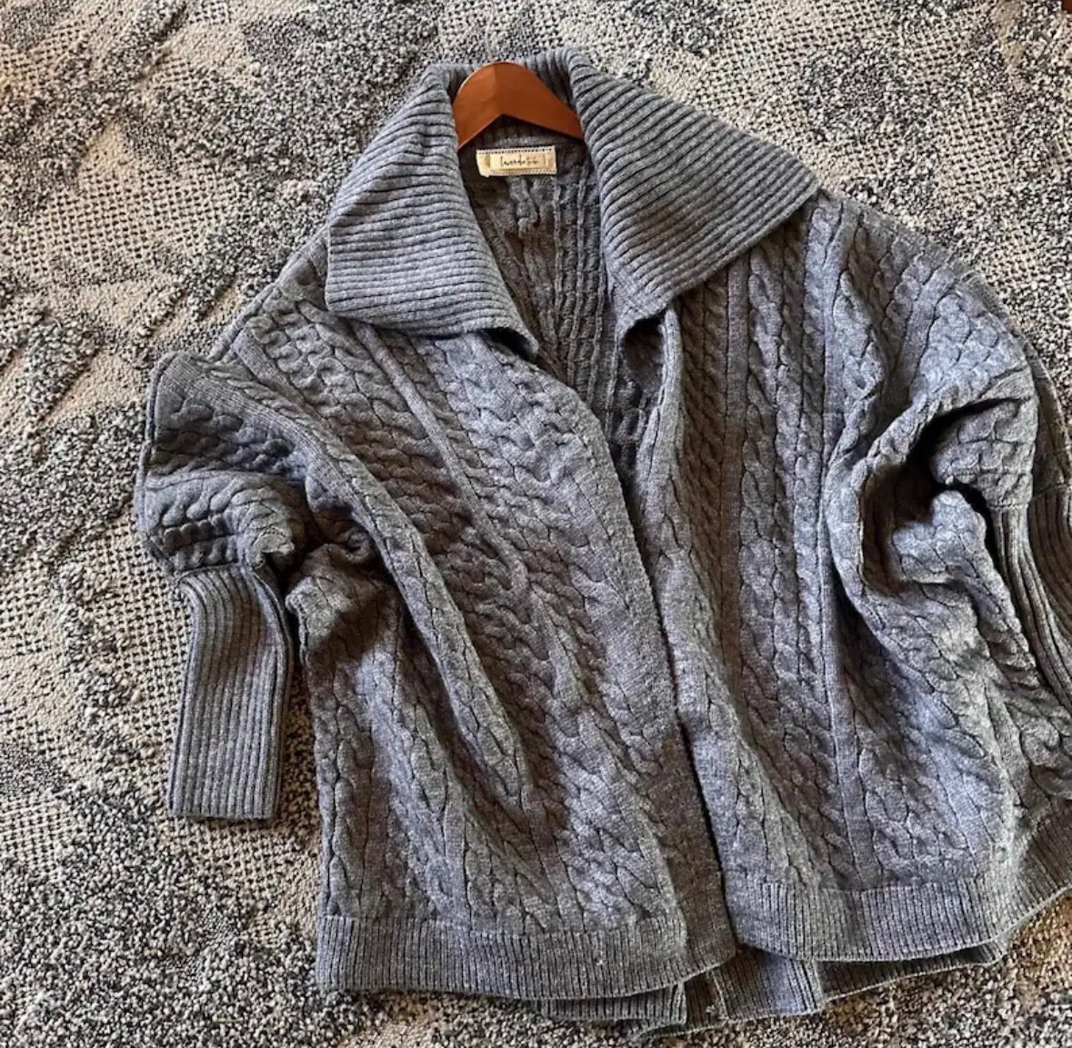 Gray cable knit cardigan on a textured surface