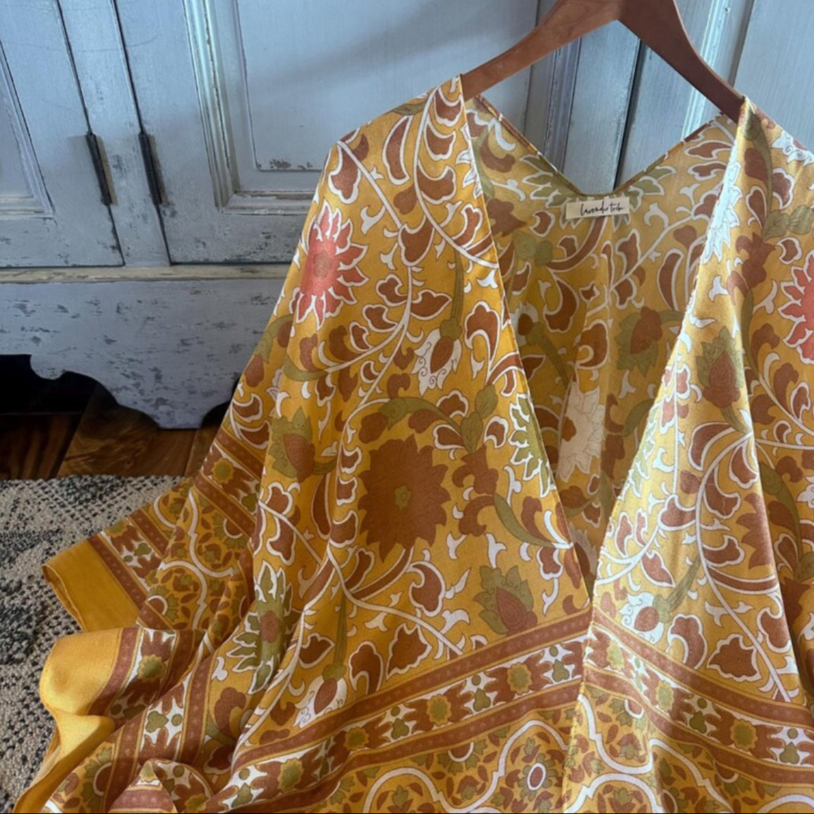 Yellow patterned fabric draped over a wooden hanger against a rustic background.