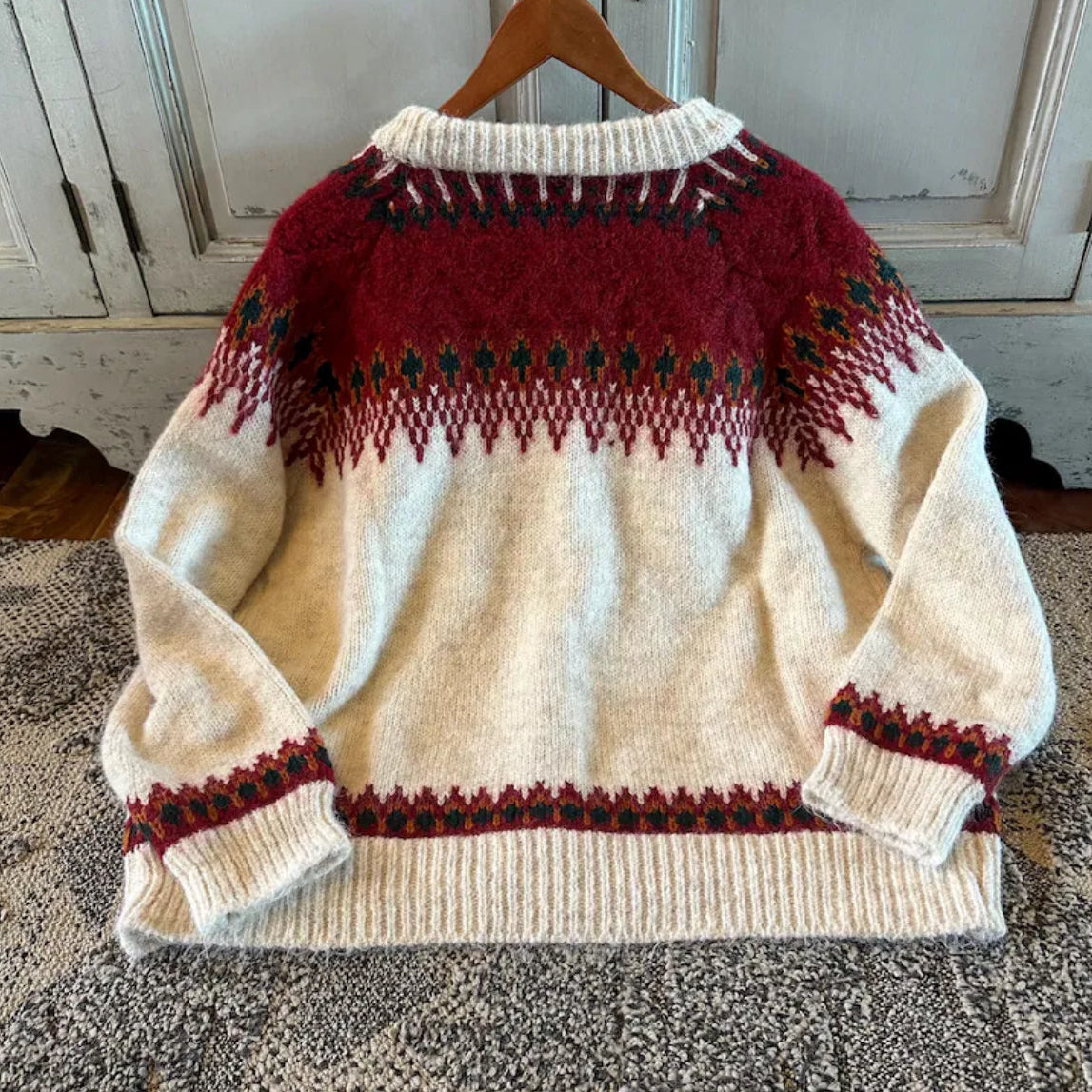 Knitted sweater with red and black patterns on a hanger