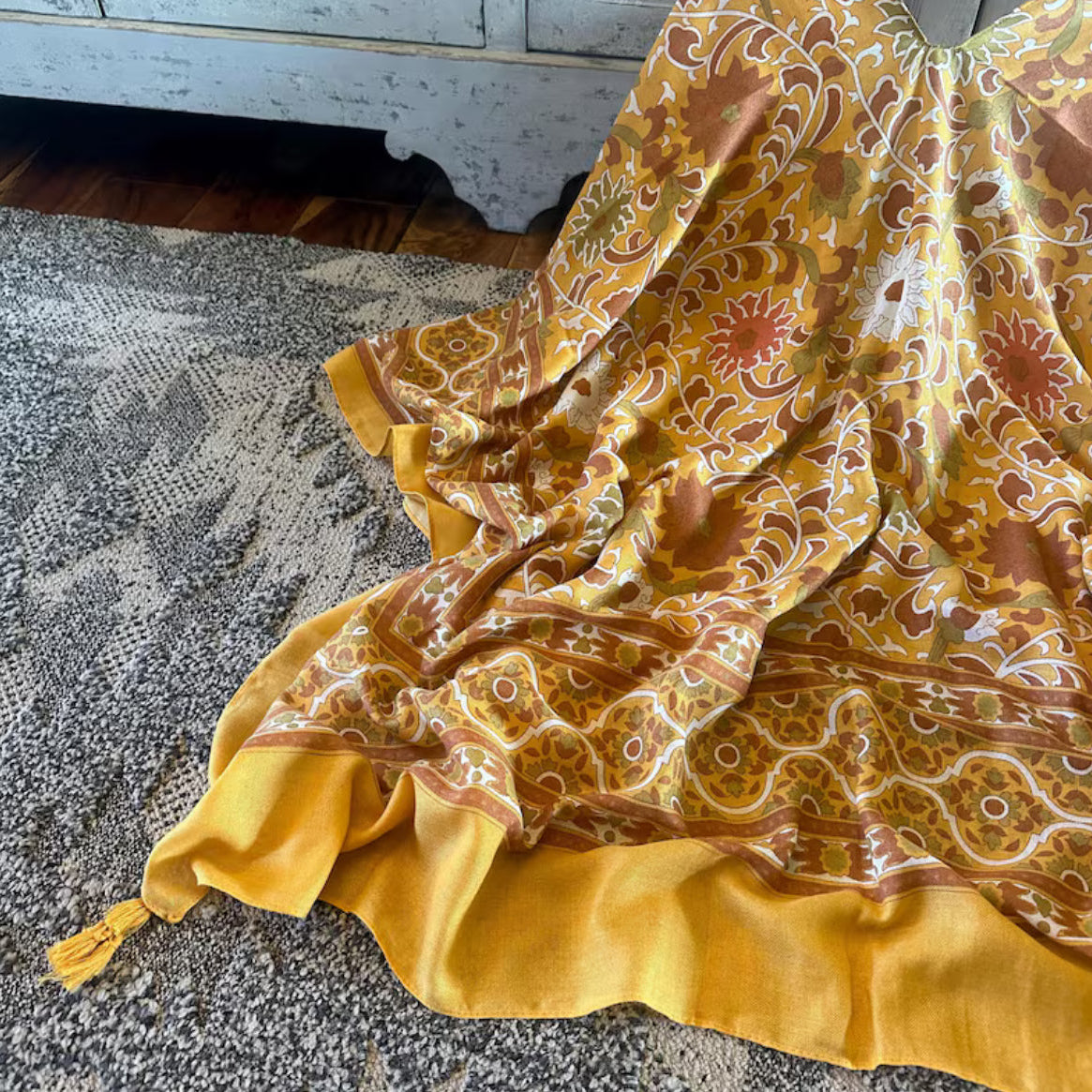 Yellow patterned fabric draped over a surface with a textured background