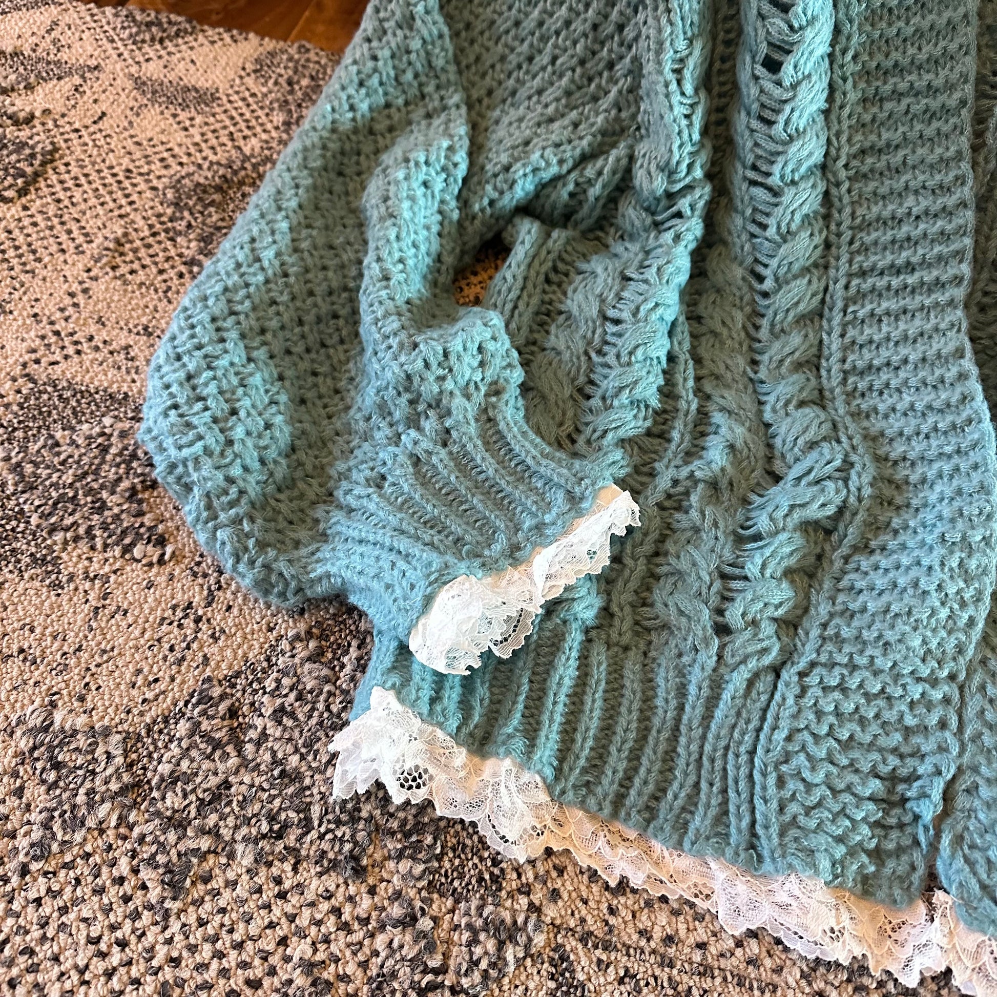 Knitted sweater with lace trim on a textured surface