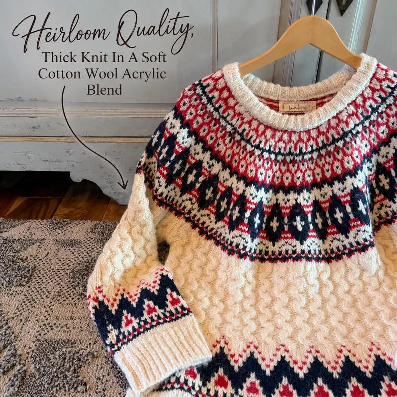 A thick-knit crewneck sweater hanging on a wooden hanger, featuring a cream base with red and navy blue Fair Isle style patterns. Text overlay on the top left reads 'Heirloom Quality, Thick Knit In A Soft Cotton Wool Acrylic Blend'.