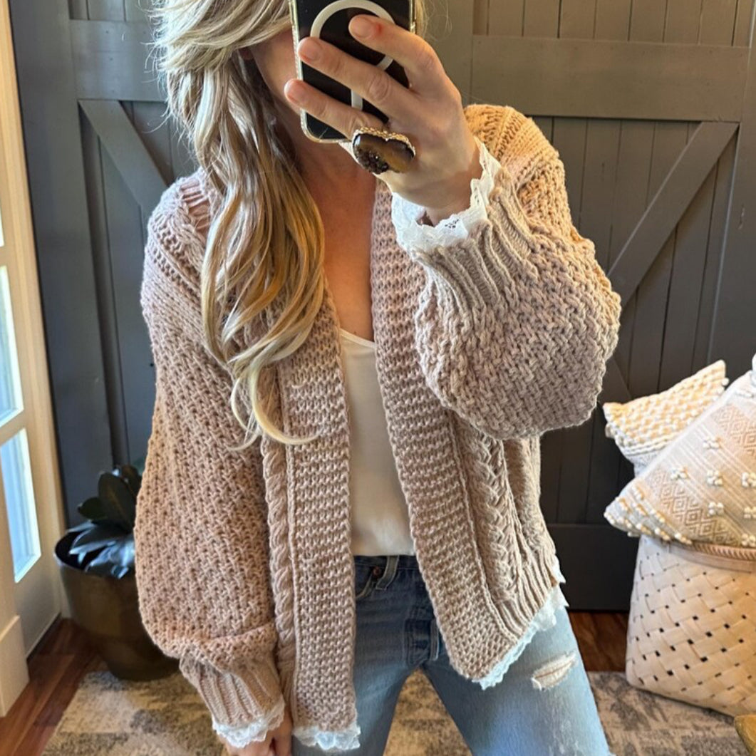 Person wearing a beige knitted cardigan in a home setting