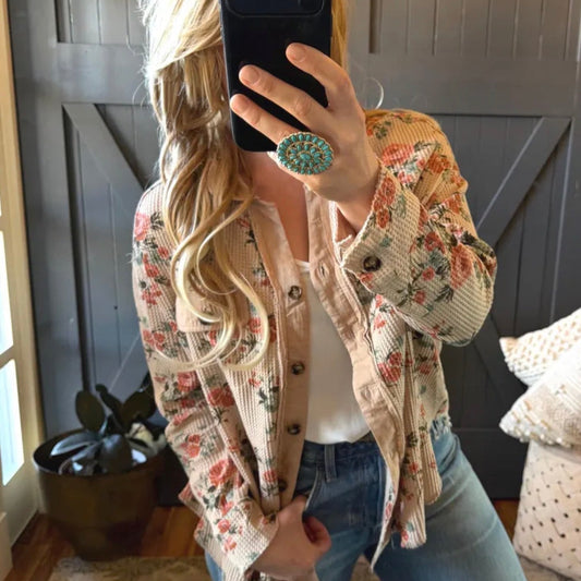 Person wearing a floral jacket and blue jeans taking a mirror selfie.