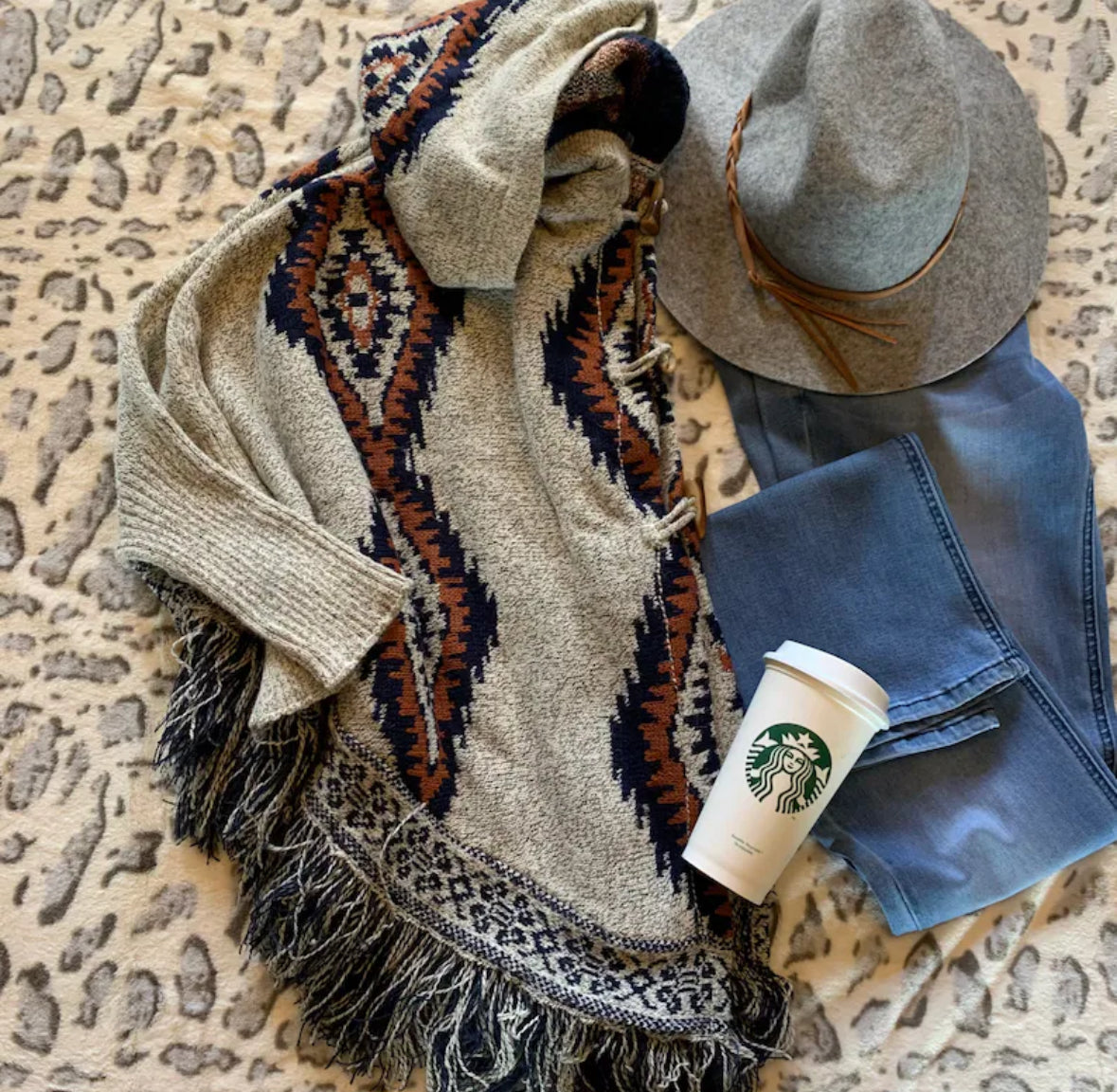 Scarf, hat, and Starbucks cup on a textured surface