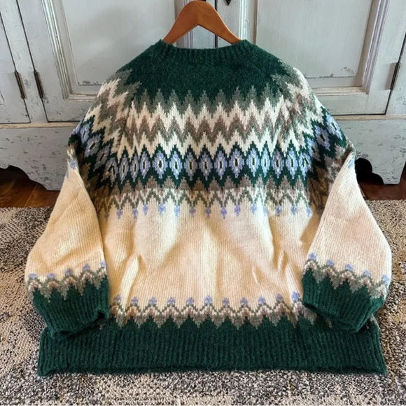 Knitted sweater with a pattern on a wooden hanger against a rustic background