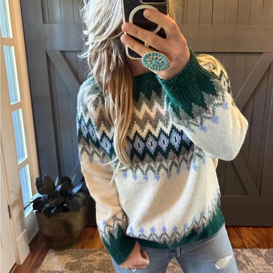 Person wearing a patterned sweater taking a mirror selfie indoors.