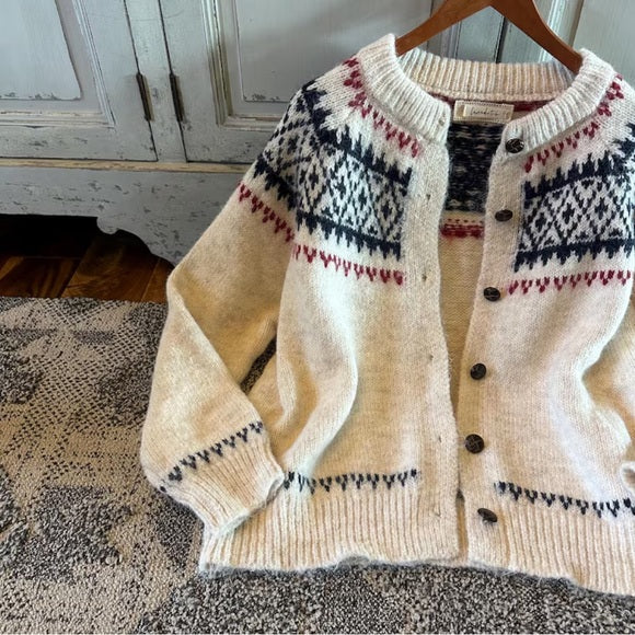 Knitted cardigan with patterned design on a wooden hanger against a rustic background