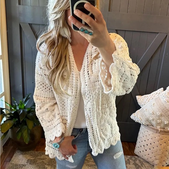Person wearing a beige crochet cardigan in a home setting