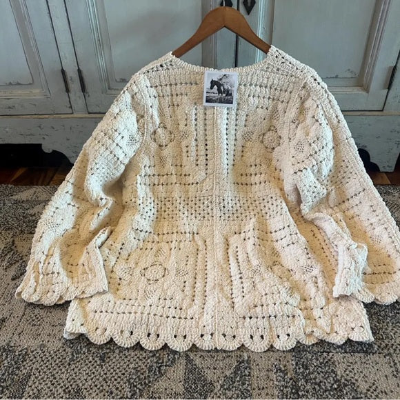 Beige crochet sweater on a hanger with a wooden background