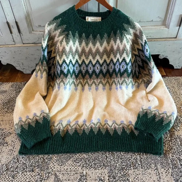 Patterned sweater on a wooden hanger against a rustic wooden wall.